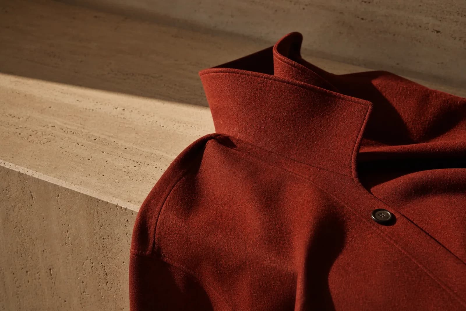Rust-red wool coat detail showing the sculptural collar and finish